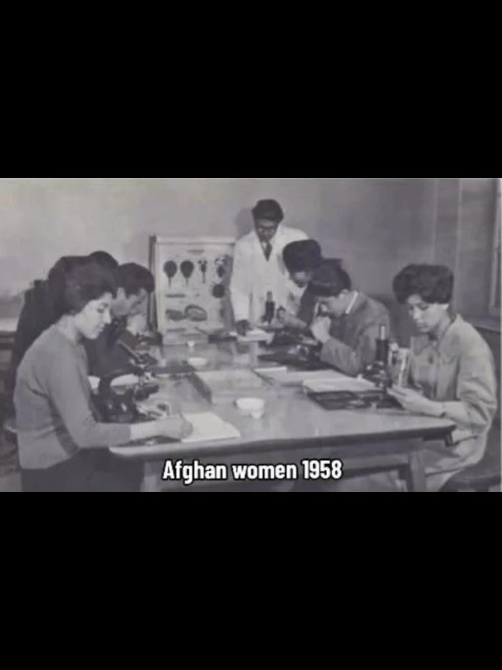 Afghan women in 1958 sitting at university laboratory desks using microscopes, wearing Western-style modest dress with hair visible.