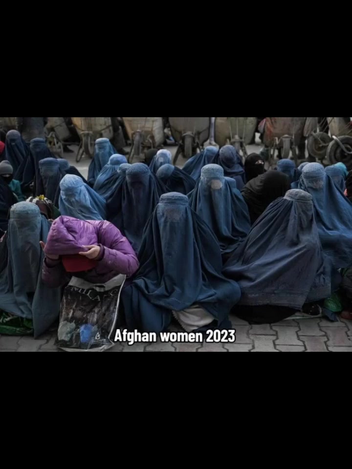 A large group of Afghan women in 2023, all wearing blue burqas that cover their entire bodies including faces, gathered in a public space.