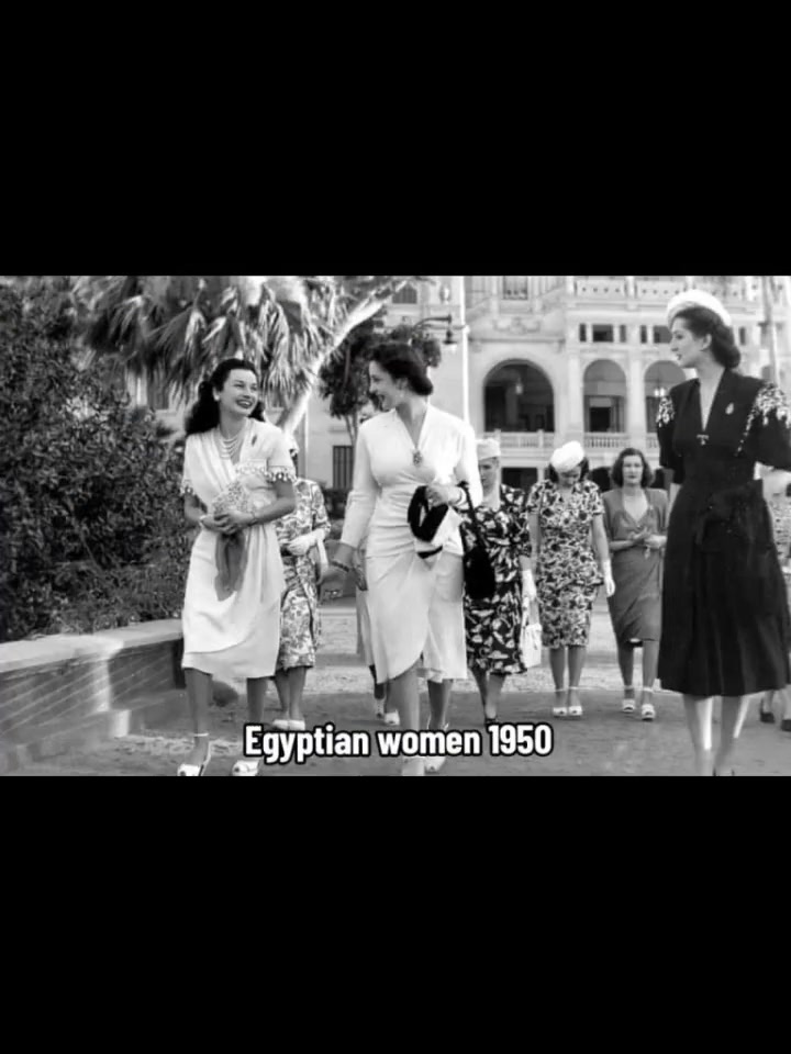 Egyptian women in 1950 walking outdoors in Western dress — fitted dresses, hair visible, no headscarves — smiling.